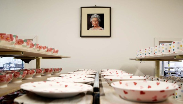 A portrait of Britain's Queen Elizabeth hangs in the Decorating Studio where mugs to commemorate the wedding of Britain's Prince Harry and Meghan Markle are being made at the Emma Bridgewater Factory, in Hanley, Stoke-on-Trent, Britain March 28, 2018. Picture taken March 28, 2018. REUTERS/Carl Recine