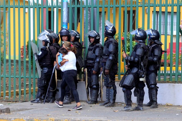 Una mujer sostiene a su hijo mientras pasa junto a la policía antidisturbios durante una protesta contra las reformas que implementan cambios en los planes de pensiones del Instituto Nicaragüense de Seguridad Social (INSS) en Managua, Nicaragua, el 19 de abril de1818. REUTERS / Oswaldo Rivas