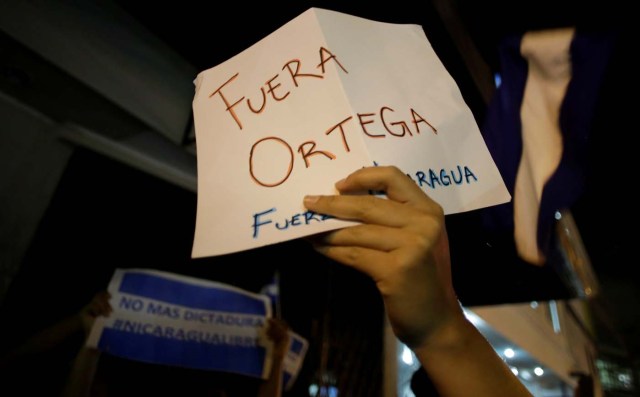 Nicaraguans living in Costa Rica hold a sign that reads "Out Ortega" during a demonstration in support of Nicaraguans protesting against the government of President Daniel Ortega, in front of the Nicaragua Embassy in San Jose, Costa Rica April 20, 2018. REUTERS/Juan Carlos Ulate