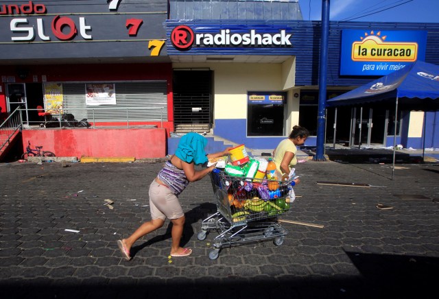 A woman with goods looted from a store walks pushing a shopping trolley along a street after protests over a reform to the pension plans of the Nicaraguan Social Security Institute (INSS) in Managua, Nicaragua April 22, 2018. REUTERS/Jorge Cabrera
