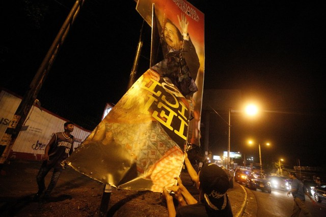 Los manifestantes vandalizan una señal del presidente nicaragüense Daniel Ortega durante una protesta contra su gobierno y la violencia policial en Managua, Nicaragua el 23 de abril de 2018. REUTERS / Jorge Cabrera