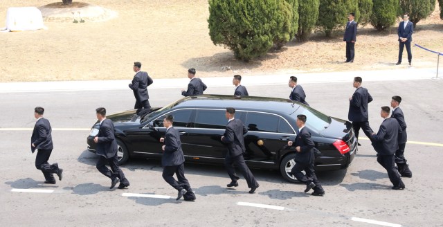 Personal de seguridad corre junto a un vehículo que transporta al líder norcoreano Kim Jong Un en la aldea de tregua de Panmunjom dentro de la zona desmilitarizada que separa las dos Coreas, Corea del Sur, 27 de abril de 2018. Korea Summit Press Pool / Pool vía Reuters