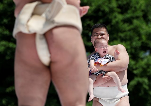 A baby cries in the arms of an amateur sumo wrestler during a baby crying contest at Sensoji temple in Tokyo, Japan, April 28, 2018. In the contest two wrestlers each hold a baby while a referee makes faces and loud noises to make them cry. The baby who cries the loudest wins. The ritual is believed to aid the healthy growth of the children and ward off evil spirits. 160 children took part in the event in this year, the organiser said. REUTERS/Issei Kato