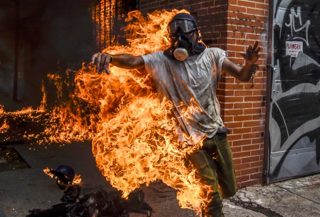 Un manifestante se incendia después de que el tanque de gasolina de una motocicleta de la policía explotó durante los enfrentamientos en una protesta contra el presidente venezolano, Nicolás Maduro, en Caracas el 3 de mayo de 2017. La furiosa oposición de Venezuela se unió el miércoles prometiendo protestas callejeras contra el plan del presidente Nicolás Maduro para reescribir la constitución y acusarlo de eludir las elecciones para aferrarse al poder a pesar de los disturbios. / AFP PHOTO / JUAN BARRETO