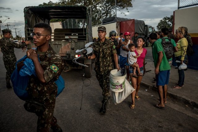 Los soldados brasileños ayudan a los migrantes venezolanos a cargar sus pertenencias en los autobuses que van hacia São Paulo. Credit Meridith Kohut para The New York Times