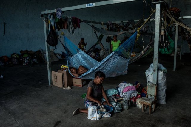 Las familias venezolanas cocinan y descansan en un refugio diseñado para migrantes indígenas en Pacaraima. Credit Meridith Kohut para The New York Times