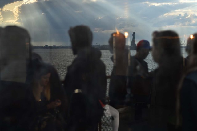 People ride the Staten Island Ferry while passing the Statue of Liberty, in New York City, on April 28, 2018. / AFP PHOTO / HECTOR RETAMAL