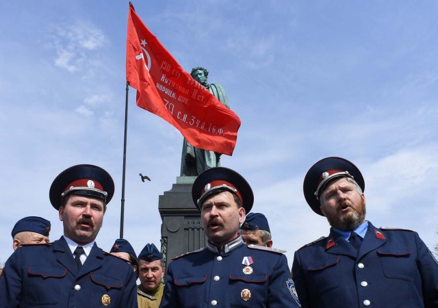 Cossacks sing in front of a monument of poet Alexander Pushkin some 30 minutes before the start of an unauthorized anti-Putin rally called by opposition leader Alexei Navalny on May 5, 2018 in Moscow, two days ahead of Vladimir Putin's inauguration for a fourth Kremlin term. / AFP PHOTO / Kirill KUDRYAVTSEV