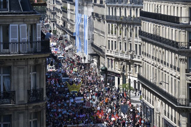 A man stands on a balcony to take photographs as thousands demonstrate along a main thoroughfare in the French capital Paris during a rally dubbed a "Party for Macron" against the policies of the French president on the first anniversary of his election, on May 5, 2018. Thousands of people demonstrated in central Paris amid a heavy police presence to protest against President Emmanuel Macron's sweeping reforms, a year after he came to office. / AFP PHOTO / Olivier MORIN