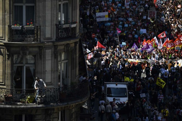 A person standing on a balcony takes photographs as thousands demonstrate along a main thoroughfare in the French capital Paris during a rally dubbed a "Party for Macron" against the policies of the French president on the first anniversary of his election, on May 5, 2018. Thousands of people demonstrated in central Paris amid a heavy police presence to protest against President Emmanuel Macron's sweeping reforms, a year after he came to office. / AFP PHOTO / Olivier MORIN