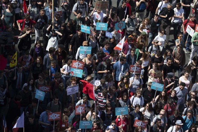 People carrying banners demonstrate along a main thoroughfare in the French capital Paris during a rally dubbed a "Party for Macron" against the policies of the French president on the first anniversary of his election, on May 5, 2018. Thousands of people demonstrated in central Paris amid a heavy police presence to protest against President Emmanuel Macron's sweeping reforms, a year after he came to office. / AFP PHOTO / Olivier MORIN