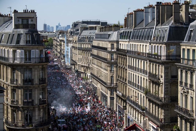 Thousands of people some holding up banners demonstrate along a main thoroughfare in the French capital Paris during a rally dubbed a "Party for Macron" against the policies of the French president on the first anniversary of his election, on May 5, 2018. Thousands of people demonstrated in central Paris amid a heavy police presence to protest against President Emmanuel Macron's sweeping reforms, a year after he came to office. / AFP PHOTO / Olivier MORIN