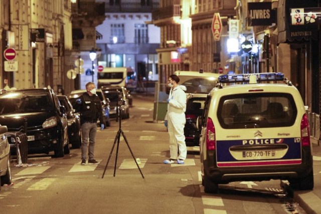 Un oficial forense (R) y un policía francés (L) se paran junto a un índice de referencia numerado y una cámara en un trípode en la calle Saint Augustin en París después de que una persona murió y varias resultaron heridas por un hombre armado con un cuchillo, fue asesinado a tiros por la policía en París el 12 de mayo de 2018. / AFP PHOTO / GEOFFROY VAN DER 