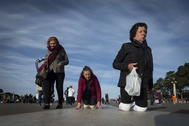 Los peregrinos se arrastran por la acera en su camino hacia el santuario de Fátima el 13 de mayo de 2018. Miles de peregrinos se reunieron en el Santuario de Fátima para celebrar el aniversario del milagro de Fátima cuando tres niños pastores afirmaron haber visto a la Virgen María en mayo de 1917. / AFP PHOTO / MIGUEL RIOPA