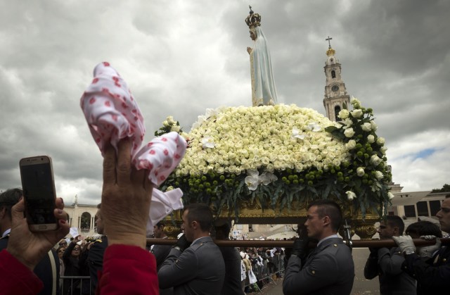 La estatua de Nuestra Señora de Fátima se lleva a cabo durante una ceremonia masiva en el santuario de Fátima en Fátima, en el centro de Portugal, el 13 de mayo de 2018. Miles de peregrinos se reunieron en el Santuario de Fátima para celebrar el aniversario del milagro de Fátima cuando tres niños pastores afirmaron haber visto a la Virgen María en mayo de 1917. / AFP PHOTO / MIGUEL RIOPA
