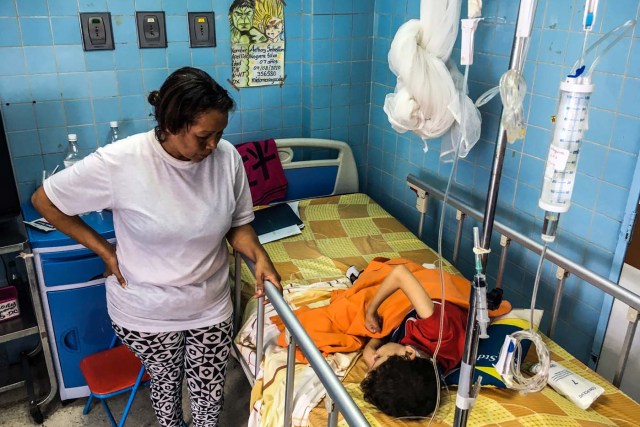 A woman stands next to her son at a neurosurgery room of the "Dr. JM de los Rios" Children's Hospital in Caracas on April 10, 2018. The crisis in Venezuela has hit children's health, with an increase of 30,12% in child mortality according to the most recent official sources. / AFP PHOTO / FEDERICO PARRA