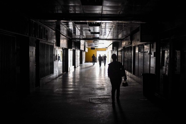 A woman walks inside of a mall during a power outage in Maracaibo, Venezuela on May 3, 2018. Amid blackouts, skyrocketing prices, shortage of food, medicine and transportation, Venezuelans go to elections next May 20 anguished to survive one of the worst crisis in the oil country. / AFP PHOTO / Federico PARRA