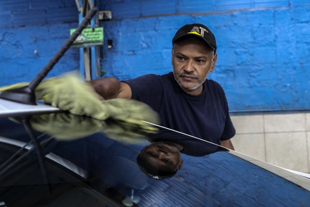 Venezuelan Carlos Figueroa cleans a car at a car wash in Medellin, Colombia, on May 15, 2018. Exiled Venezuelans have no expectations of the presidential election taking place next May 20 in their home country. / AFP PHOTO / JOAQUIN SARMIENTO