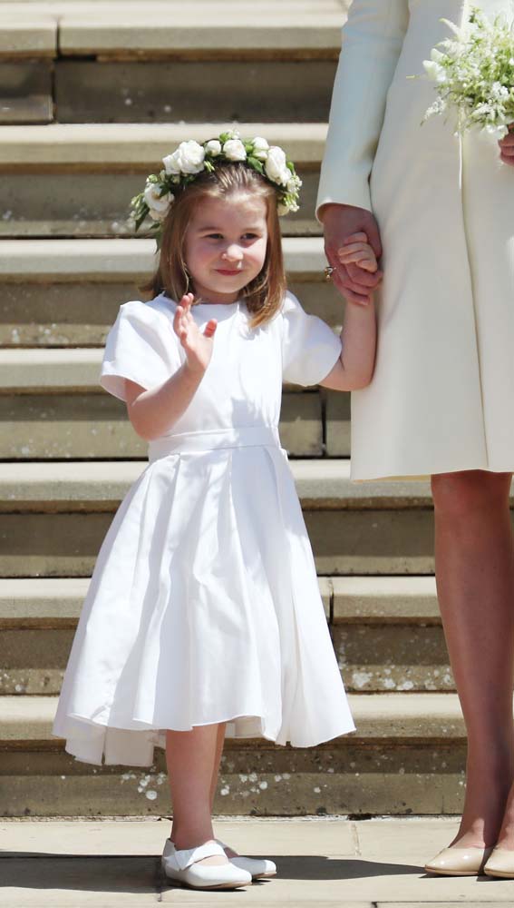 Princess Charlotte of Cambridge (L) waves holding the hand of her mother Britain's Catherine, Duchess of Cambridge, (R) after attending the wedding ceremony of Britain's Prince Harry, Duke of Sussex and US actress Meghan Markle at St George's Chapel, Windsor Castle, in Windsor, on May 19, 2018. / AFP PHOTO / POOL / Jane Barlow
