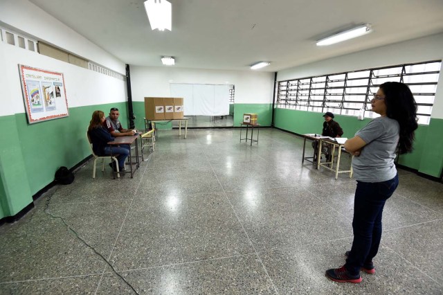 Venezuelan electoral officials waits for voters at an empty polling station during the presidential elections in Caracas on May 20, 2018 Venezuelans, reeling under a devastating economic crisis, began voting Sunday in an election boycotted by the opposition and condemned by much of the international community but expected to hand deeply unpopular President Nicolas Maduro a new mandate / AFP PHOTO / Juan BARRETO