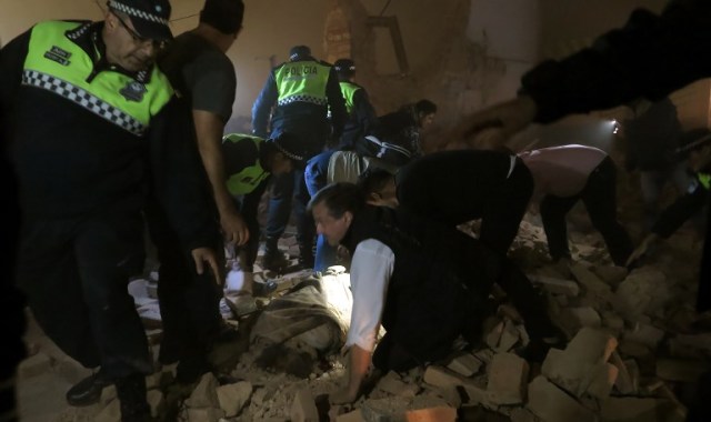 Police and passers-by look for victims in the rubble, minutes after the collapse of the old Parravicini movie theater building, in Tucuman, Argentina on May 23, 2018. / AFP PHOTO / Walter Monteros