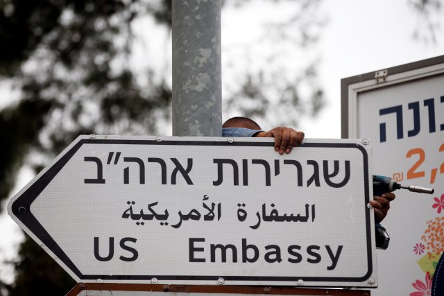 Un trabajador cuelga una señal de tráfico que dirige a la embajada de EE. UU., En el área del consulado de EE. UU. En Jerusalén, el 7 de mayo de 2018. REUTERS / Ronen Zvulun / File Photo