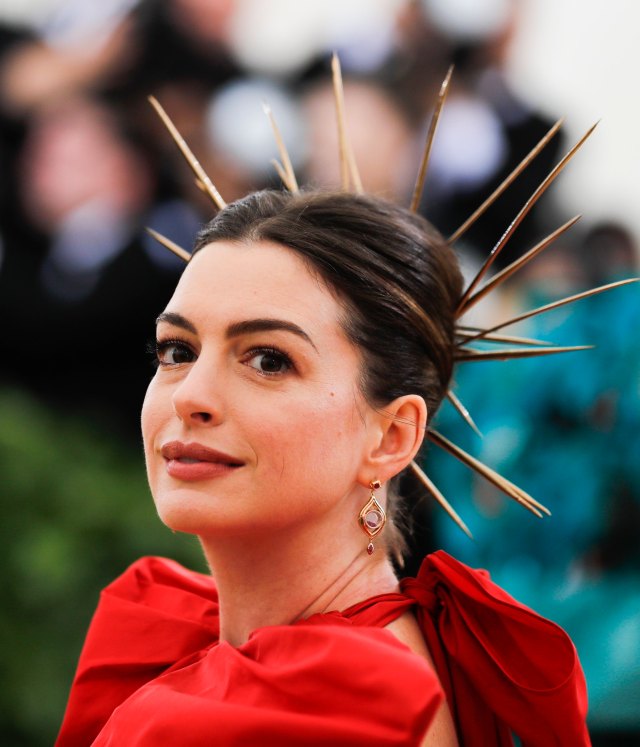 La actriz Anne Hathaway opta por una corona de espinas para complementar su voluminoso diseño rojo de Valentino. REUTERS/Carlo Allegri