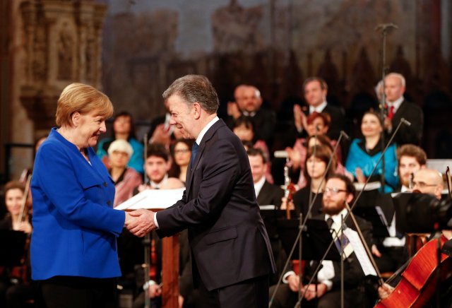La canciller alemana, Angela Merkel, es recibida por el presidente colombiano Juan Manuel Santos después de que recibió el premio "Lámpara de la paz" de los monjes católicos en la Basílica de San Francisco en Asís, Italia, el 12 de mayo de 2018. REUTERS / Yara Nardi