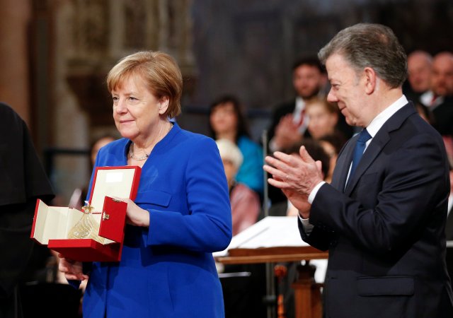 La canciller alemana, Angela Merkel, recibió un premio "Lámpara de la paz" recibido de los monjes católicos mientras era recibida por el presidente colombiano Juan Manuel Santos en la Basílica de San Francisco en Asís, Italia, el 12 de mayo de 2018. REUTERS / Yara Nardi