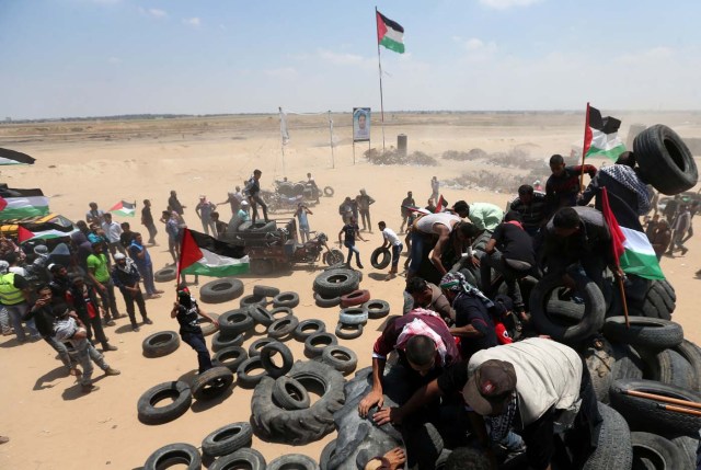 Palestinians collect tires to be burnt during a protest marking the 70th anniversary of Nakba, at the Israel-Gaza border in the southern Gaza Strip May 15, 2018. REUTERS/Ibraheem Abu Mustafa