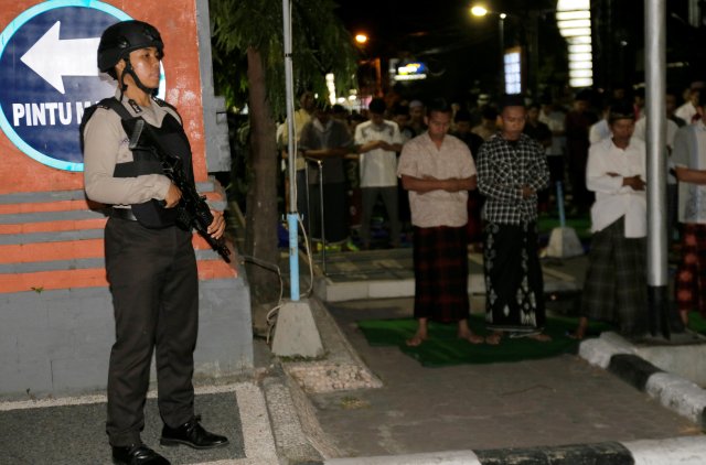 Police guard while Muslims pray at the first day of the holy fasting month of Ramadan at a mosque near Bali Police Headquarters in Denpasar, on the resort island of Bali, Indonesia May 16, 2018. REUTERS/Johannes P. Christo