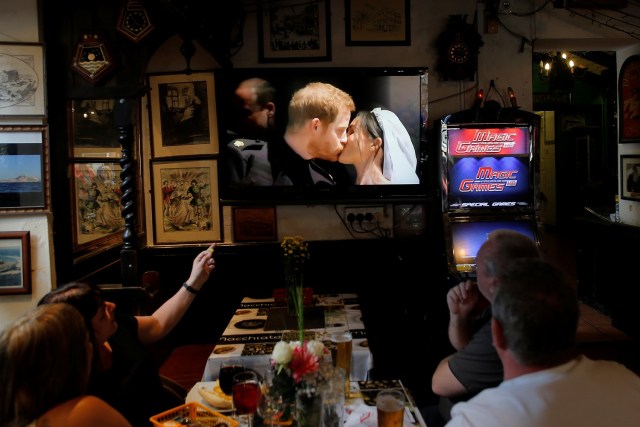 British tourists watch as Britain's Prince Harry and Meghan Markle kiss on the steps of St George's Chapel in Windsor Castle after their wedding, on a television in a restaurant in the British overseas territory of Gibraltar, historically claimed by Spain May 19, 2018. REUTERS/Jon Nazca