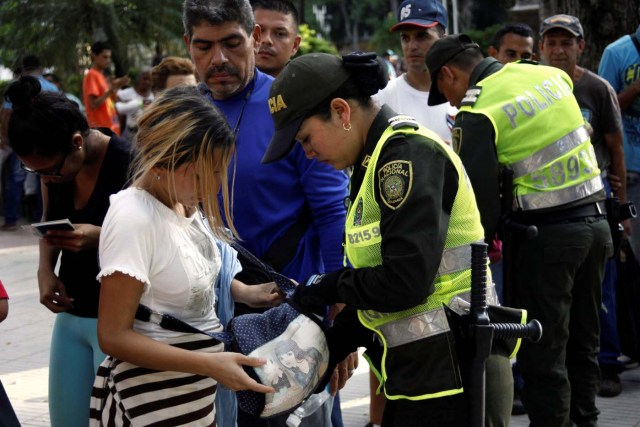 A Colombian police officer inspects the bag of a woman as Venezuelans queue outside an exchange house in Cucuta, Colombia May 17, 2018. Picture taken May 17, 2018. REUTERS/Carlos Eduardo Ramirez