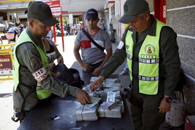 Venezuelan National Guards confiscate stacks of bolivar notes, as they inspect the luggage of a couple at the customs in San Antonio del Tachira, Venezuela May 16, 2018. Picture taken May 16, 2018. REUTERS/Carlos Eduardo Ramirez