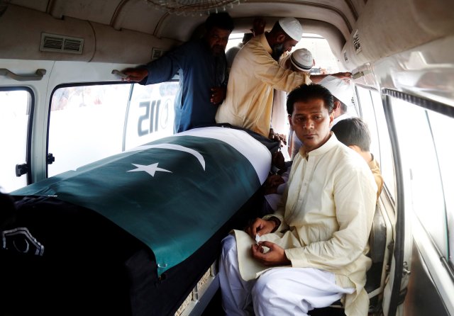 Aziz Sheikh father of Sabika Aziz Sheikh, a Pakistani exchange student, who was killed with others when a gunman attacked Santa Fe High School in Santa Fe, Texas, U.S., sits in an ambulance next to her coffin, wrapped in national flag, during a funeral in Karachi, Pakistan May 23, 2018. REUTERS/Akhtar Soomro