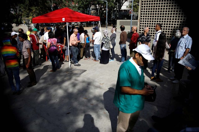 Los ciudadanos venezolanos esperan para registrarse en un "Punto Rojo", un área establecida por el partido del presidente Nicolás Maduro, para verificar que emitan sus votos durante las elecciones presidenciales en Caracas, Venezuela, el 20 de mayo de 2018. REUTERS / Carlos Garcia Rawlins