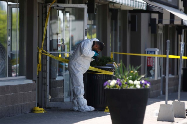 A police forensic investigator photographs evidence at Bombay Bhel restaurant, where two unidentified men set off a bomb late Thursday night, wounding fifteen people, in Mississauga, Ontario, Canada May 25, 2018. REUTERS/Mark Blinch