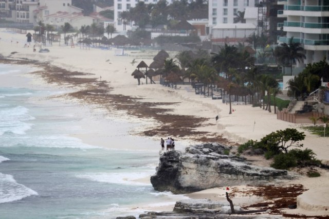 Turistas observan la playa desde una roca, mientras la tormenta subtropical Alberto se aproxima a Cancun, México, 25 de mayo, 2018. REUTERS/Israel Leal