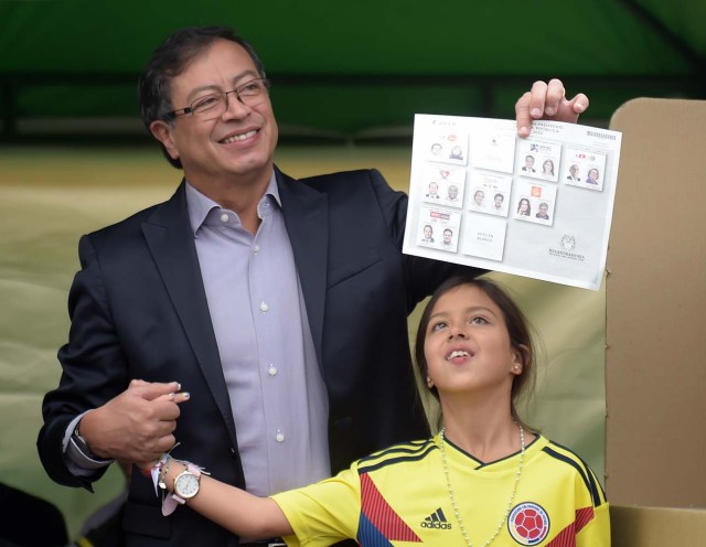 Colombian presidential candidate Gustavo Petro shows his ballot as he votes accompanied by one of his daughters, at a polling station in Bogota during presidential elections in Colombia on May 27, 2018. / AFP PHOTO / Raul ARBOLEDA