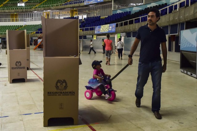 A man with his daughter is seen at a polling station in Cali, Valle del Cauca Department, during presidential elections in Colombia on May 27, 2018. Voters went to the polls Sunday to choose a new president of Colombia in a divisive election that is likely to weigh heavily on the future of the government's fragile peace deal with the former rebel movement FARC. / AFP PHOTO / Luis ROBAYO