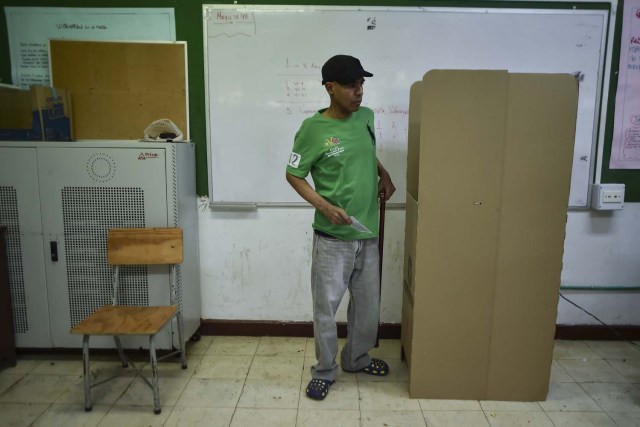 A man votes at a polling station in Cali, Valle del Cauca Department, during presidential elections in Colombia on May 27, 2018. Voters went to the polls Sunday to choose a new president of Colombia in a divisive election that is likely to weigh heavily on the future of the government's fragile peace deal with the former rebel movement FARC. / AFP PHOTO / Luis ROBAYO