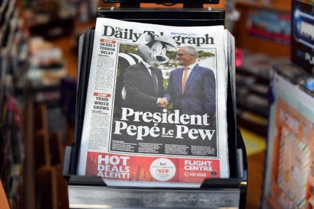 A copy of The Daily Telegraph is seen on a newstand with a nearly full-page photo of French President Emmanuel Macron with the cartoon head of Pepe le Pew, the lovelorn French skunk, in Sydney on May 3, 2018. Macron on May 3 laughed off global amusement after he described the wife of Australian Prime Minister Malcolm Turnbull as "delicious" during a visit to Sydney. / AFP PHOTO / SAEED KHAN