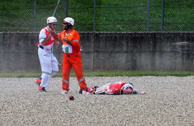 Medical staff stand by lying Ducati Team's italian rider Michele Pirro (R) after a crash during a free practice session ahead of the Italian MotoGP Grand Prix at the Mugello racetrack in Scarperia e San Piero, on June 1, 2018. / AFP PHOTO / TIZIANA FABI