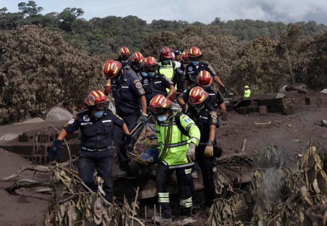 Los bomberos municipales portan el cadáver de una víctima de la erupción del volcán Fuego recuperada durante un registro en el pueblo cubierto de ceniza de San Miguel Los Lotes, en el departamento de Escuintla, a unos 35 km al suroeste de Ciudad de Guatemala, el 6 de junio de 2018. Casi 200 personas están desaparecidos y al menos 75 han muerto desde que el volcán Fuego de Guatemala comenzó a erupcionar durante el fin de semana, dijeron el martes las autoridades.  Johan ORDONEZ / AFP