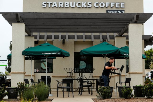 A worker puts away patio furniture at a Starbucks Corp drive-through location closes down this afternoon for anti-bias training as the coffee chain closed all 8,000 of their company-owned cafes in the U.S. including this location in Oceanside, California, U,S. May 29, 2018. REUTERS/Mike Blake