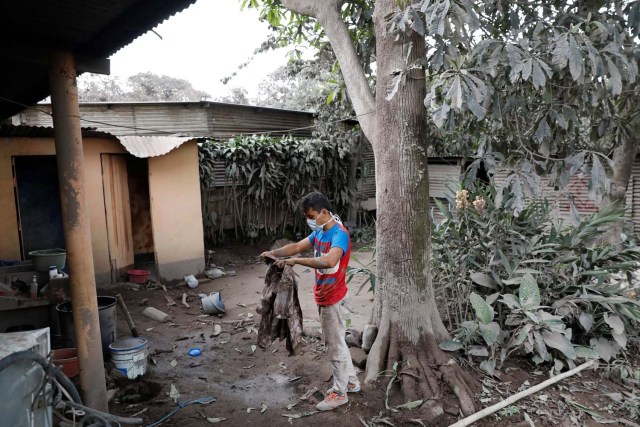 Jonathan Castellanos mira su ropa cuando visita su casa dañada después de la erupción del volcán Fuego en El Rodeo en Escuintla, Guatemala el 6 de junio de 2018. REUTERS / Carlos Jasso