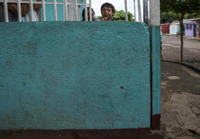 Un niño se asoma en un muro con un impacto de bala hecho por desconocidos en un barrio de la capital hoy, 11 de junio de 2018, en Managua (Nicaragua). Este lunes por la mañana la Policía Nacional y grupos "parapoliciales" atacaron los llamados "barrios orientales" de Managua con armas de guerra, en respuesta a múltiples barricadas que edificó la población en las calles para impedir el paso de fuerzas de choque oficialistas. EFE/Jorge Torres.