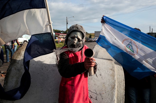 A masked protester poses for a photo as he stands at a barricade blocking the Pan-American highway during a protest against President Daniel Ortega's government in El Crucero, Nicaragua June 7, 2018. REUTERS/Oswaldo Rivas