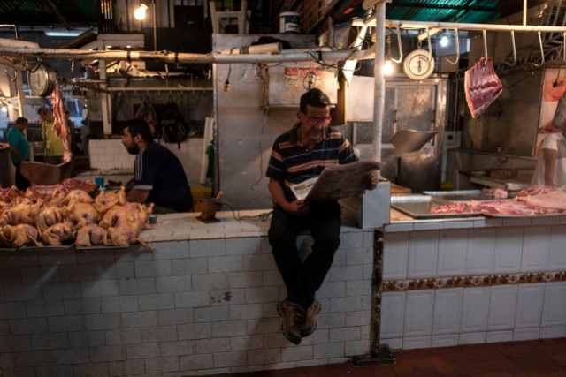 Un hombre lee un periódico en un puesto de carnicería en un mercado en San Cristóbal, Venezuela. Una moneda en colapso significa que pocos venezolanos pueden costear carne de res y pollo. A menudo, los carniceros venden la carne al costo para que no se dañe. Muchos puestos del mercado han cerrado. (Michael Robinson Chavez / The Washington Post)