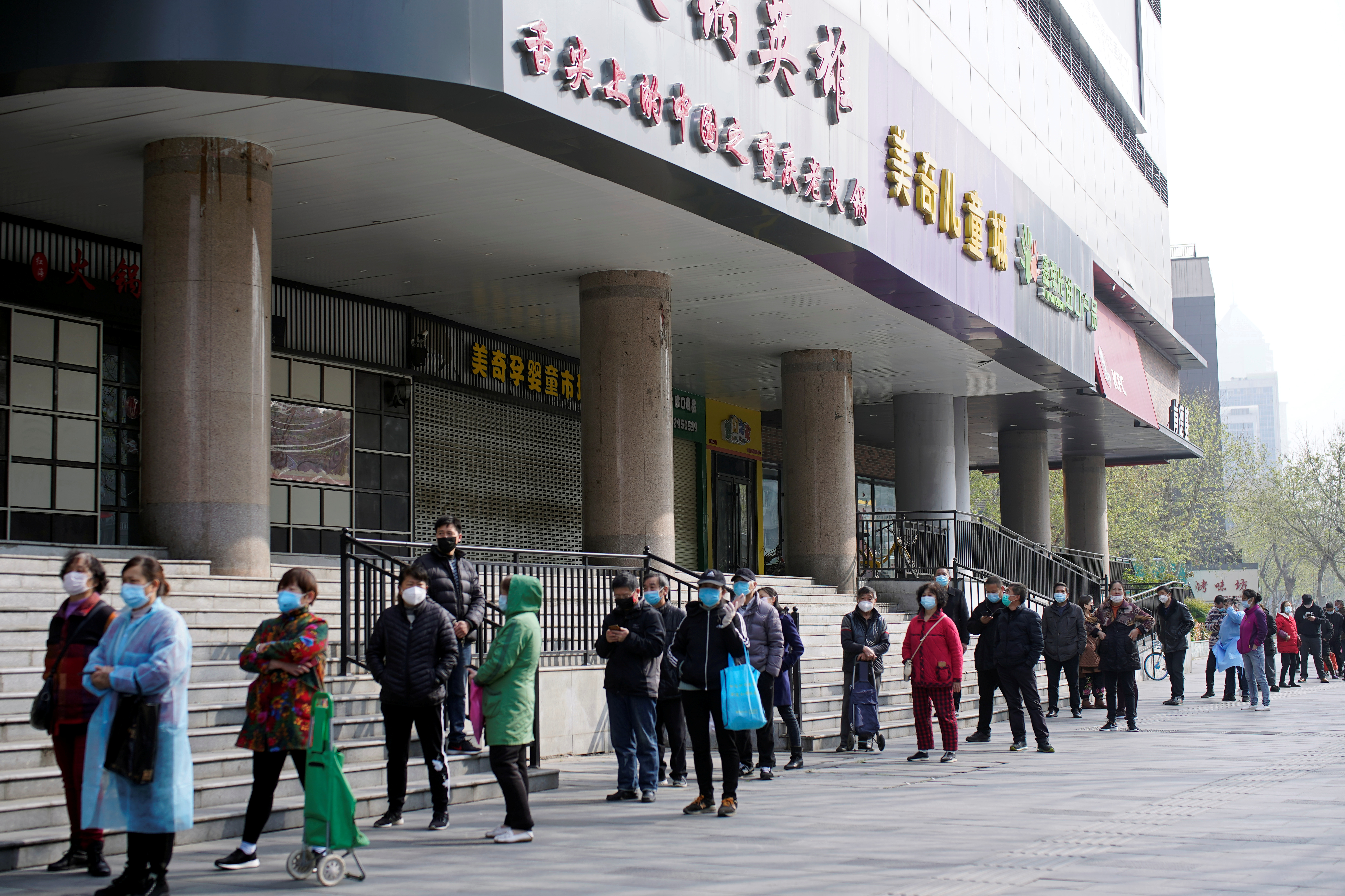 Los vecinos de Wuhan gritan por encima de una valla para hacer sus compras (Fotos)